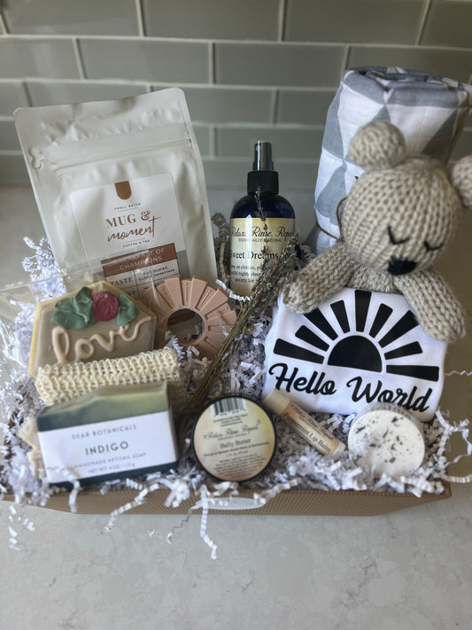 "Mama & Baby Too Gift Basket with belly butter, lavender spray, indigo soap, lip balm, shower steamer, cookie, coffee, bear lovie, onesie, teether, and swaddle blanket"